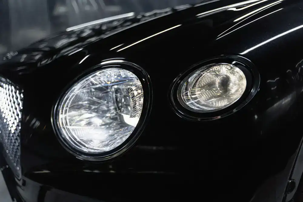 Close up of a highly polished black car hood reflecting studio lights