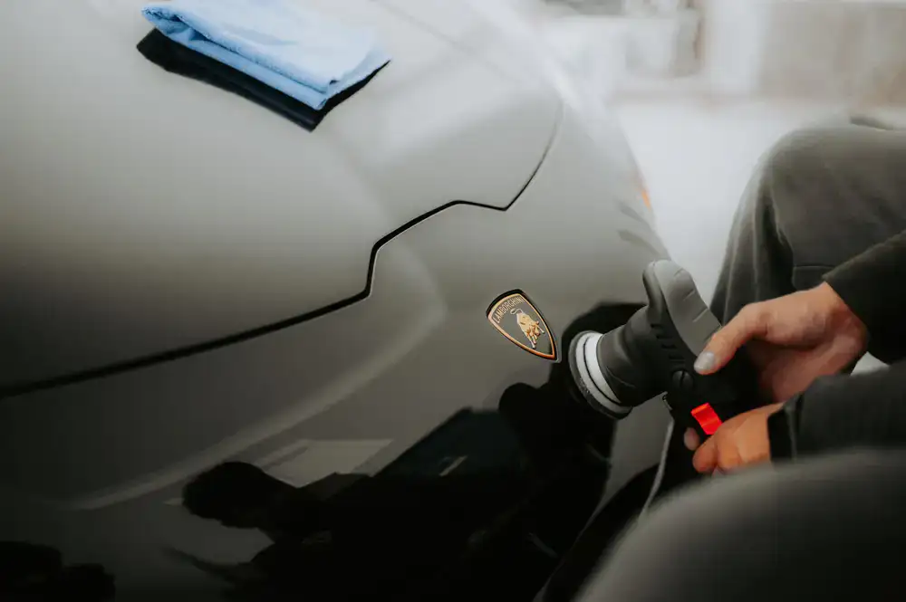 Detailer polishing a luxury car hood